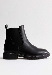 Czarny botek typu Chelsea wykonany ze gładkiej skóry, wyposażony w elastyczne boczne panele, pętelkę oraz kontrastową, białą podeszwę z przeszyciami.