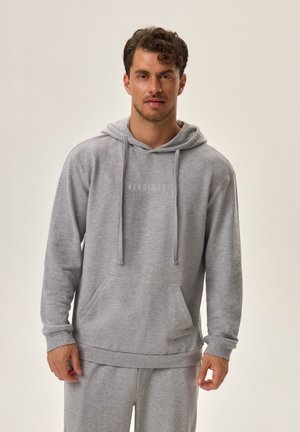 Grauer Hoodie mit Kapuze, langen Ärmeln, Kordelzügen und einer vorderen Tasche. Das Material fühlt sich weich an und hat eine leicht strukturierte Oberfläche.