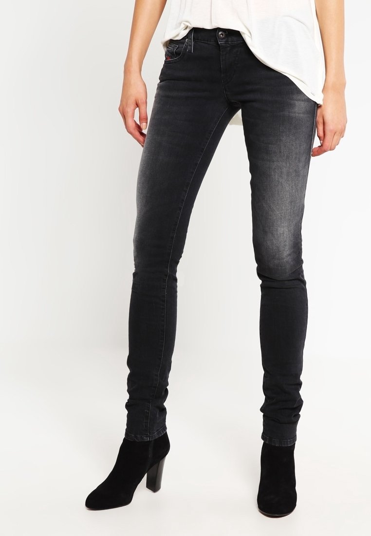 Black skinny jeans made of denim, featuring a faded finish, standard five-pocket design, and worn with black ankle boots.