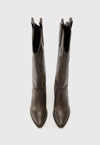 Hnědé kožené kotníkové boty s špičatými špičkami, zdobené ozdobným šitím a poutky na bocích. Texturovaný povrch s propracovanými vzory.