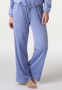 Pantaloni da pigiama in velluto morbido di colore azzurro chiaro, con una vestibilità rilassata e gambe ampie. Presentano una vita elasticizzata con cordoncino.