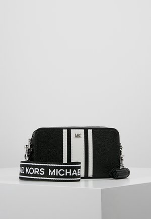 Sac bandoulière Michael Kors noir et blanc avec deux bandes blanches verticales et une sangle amovible affichant le texte "Michael Kors".