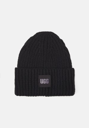 Gruba czarna dzianinowa czapka z podwiniętym mankietem, z czarną łatką z srebrnym napisem "UGG" na środku z przodu.