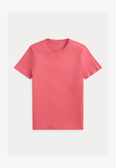 Bomullst-shirt i korallfärg, korta ärmar, rund halsringning, har en liten blå logotyp på bröstet, slät textur.