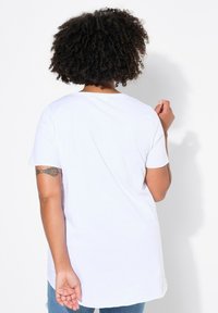 T-shirt en coton blanc à manches courtes, col rond et coupe décontractée. Texture lisse sans motifs ou accents visibles.