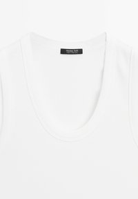Vit tanktopp av ribbat tyg med rundad halsringning och en etikett som säger "Massimo Dutti, Tillverkad i Portugal."