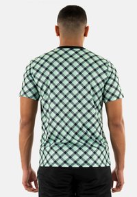 T-shirt a maniche corte verde a quadri con bordi neri, caratterizzato da un motivo a diamante in diverse tonalità di verde e nero, realizzato in un tessuto liscio.