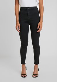 Fialové skinny džíny s vysokým pasem vyrobené z elastického denimu, s předním zapínáním na knoflík a slim fit. Hladká textura, délka nad kotníky.