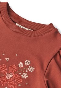 Felpa color ruggine con scollatura rotonda a costine e ricami floreali in rosa e bianco vicino alla zona del petto e delle spalle.