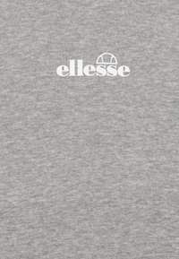 T-shirt in cotone grigio con logo "ellesse" bianco sul petto. Il tessuto ha una consistenza liscia con un sottile motivo melange.