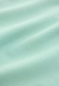 Tela tejida de color azul claro con una textura suave y un patrón sutil y uniforme; presentada en suaves pliegues para una apariencia dimensional.