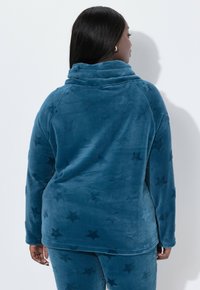 Türkiser Fleece-Pullover mit hohem Kragen, ausgestattet mit einem Sternenmuster, glatter Textur und langen Raglanärmeln. Rückansicht gezeigt.