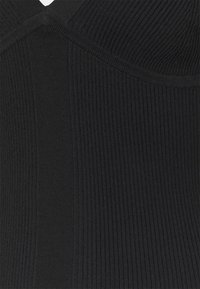 Body noir à côtes avec un design ajusté. Le tissu présente une texture côtelée verticale et un léger éclat, mettant en valeur les lignes de contour.