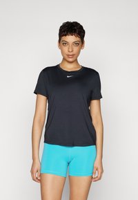 Czarna sportowa koszulka z krótkim rękawem i okrągłym dekoltem z małym białym logo, zestawiona z dopasowanymi turkusowymi szortami.