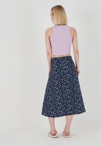 Lila ribbad crop top i kombination med en marinblå blommig midi kjol, som pryds av små vita blommor, med ett flödande tyg och en mjuk текстur.