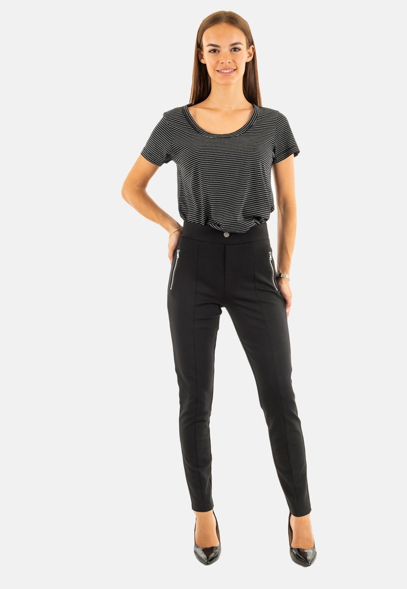 Pantaloni neri aderenti con tasche con zip, abbinati a una maglietta a maniche corte grigio e bianco a righe, entrambi realizzati in tessuto leggero.