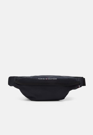 Zwarte heuptas met voorvak met rits en Tommy Hilfiger-logo in wit en rood boven in het midden.