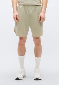 Αθλητικά σορτς σε ανοιχτό ελιά χρώμα, κατασκευασμένα από διαπνέον ύφασμα δίχτυ, με σούρα στη μέση, πλαϊνές σχισμές και άνετη, φαρδιά γραμμή για άνεση.