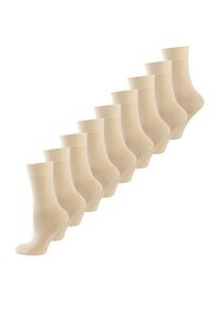 Beige ankelstrømper arrangeret i en diagonal linje, med en glat tekstur og ribbede manchetter. Hver strømpe er identisk i design.