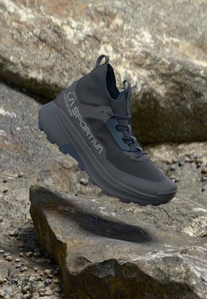 Zwarte trailrunning schoenen met een gestructureerde bovenkant, gevoerde kraag en een dikke, robuuste zool, ontworpen voor buitenactiviteiten.