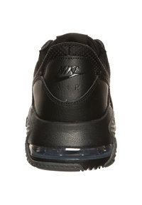 Black Nike Air sneakers featuring a smooth leather and mesh upper, rounded heel, transparent air cushioning, and embossed branding on the back.