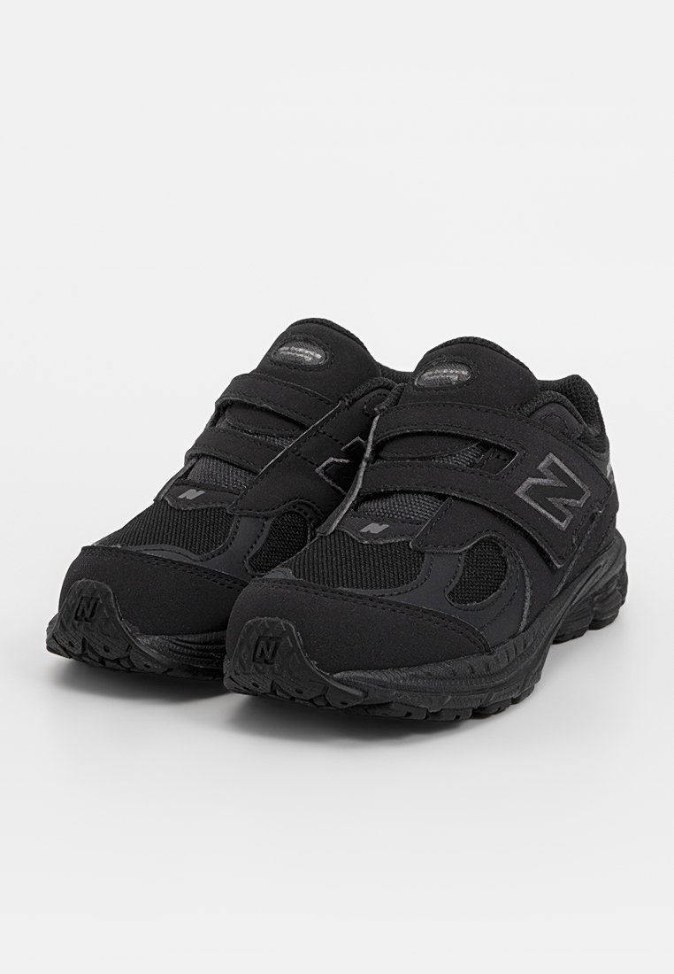 Chaussures de sport noires en combinaison de mesh et de matériaux synthétiques. Équipées de deux bandes velcro et de semelles texturées pour une meilleure adhérence.