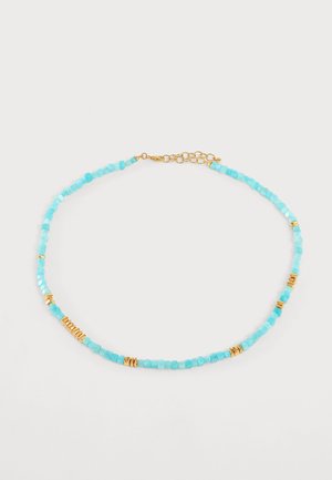 Delicate ketting met kleine turquoise kralen en gespreide gouden cilindrische kralen, met een verlengstuk van een gouden kettingsluiting op een witte achtergrond.
