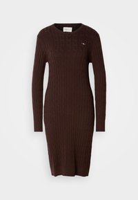 Bruine kabelgebreide sweaterjurk met lange mouwen, ronde halslijn, geribbelde zoom en een kleine logo-accent op de borst. Gestructureerd gebreid patroon.