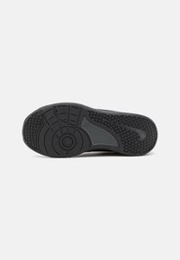 Black sneaker sole with circular and textured tread patterns, visible Nike swoosh logo on heel, set against a plain white background.