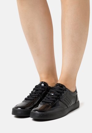 Sneaker neri in vernice con suole in gomma nera testurizzata, design con lacci e un accento con il logo sul lato.