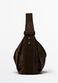 Brown suede bag with a rounded shape, flat base, and thick vertical strap featuring silver hardware and contrasting stitching.