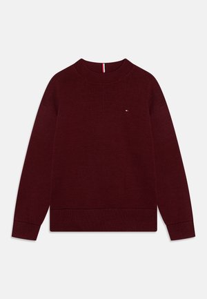 Pull en tricot bordeaux avec un col rond, des poignets et un ourlet côtelés. Petit logo discret sur la poitrine. Texture lisse et coupe décontractée.