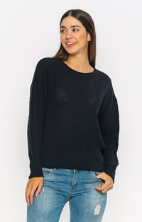 Dunkelblauer gestrickter Pullover mit Rundhalsausschnitt und gerippten Bündchen. Verfügt über ein strukturiertes Zopfmuster und wird mit verwaschenen Jeans kombiniert.