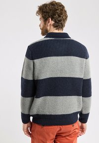 Pull en laine rayé bleu marine et gris avec une texture côtelée et un col, présentant une coupe décontractée et de larges bandes à l'ourlet.
