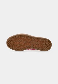 Brown rubber sole with circular grip patterns, featuring lighter tonal accents and a logo. Smooth, solid structure with a slight curve.