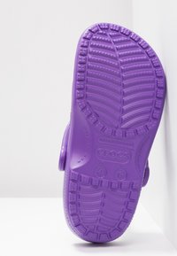 Semelle de sandale Crocs violette montrant le motif de la bande de roulement, taille 4 hommes/6 femmes, avec les inscriptions "Made in Vietnam".