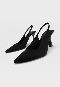 Svarta slingback-pumps med spetsig tå. Slät tygutanför, fyrkantig klack och öppen baksida för en minimalistisk look.