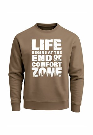 Brauner Sweatshirt mit fettem weißem Text: "DAS LEBEN BEGINNT AM ENDE DEINER KOMFORTZONE", mit Baum-Silhouetten am unteren Rand.
