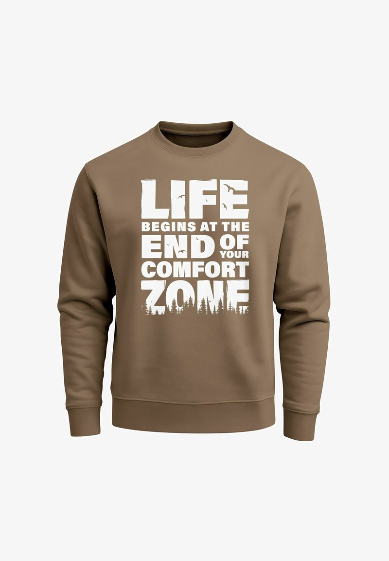 Brauner Sweatshirt mit fettem weißem Text: "DAS LEBEN BEGINNT AM ENDE DEINER KOMFORTZONE", mit Baum-Silhouetten am unteren Rand.