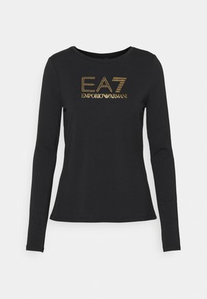 Pitkähihaista mustaa puuvillapaitaa, jossa on kullanvärinen strassilogo "EA7 EMPORIO ARMANI" edessä. Pyöreä kaula-aukko, slim fit -malli.