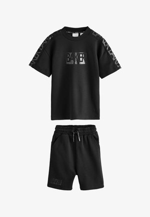 Must lühikeste varrukatega särk ja elastse vöökohaga lühikesed püksid, millel on rinnal, varrukatel ja vasaku jala esiküljel "BAKER" logo.