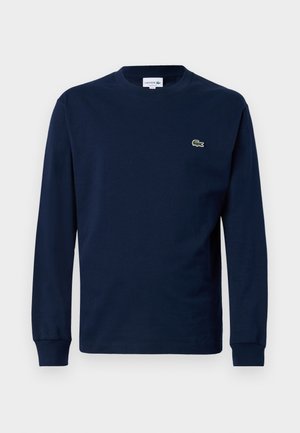 Camiseta de manga larga azul marino hecha de algodón, con cuello redondo y un pequeño logo de cocodrilo verde en el lado izquierdo del pecho.