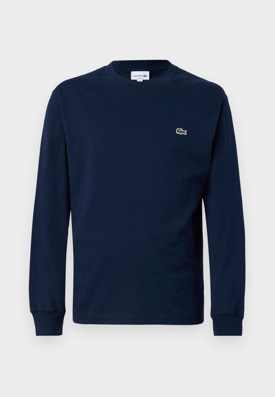 T-shirt à manches longues bleu marine en coton, avec un col rond et un petit logo de crocodile vert sur la poitrine gauche.