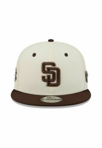 Casquette snapback blanche et marron avec logo "SD" brodé sur le devant et petits patchs sur les côtés, visière marron plate et trous de ventilation.