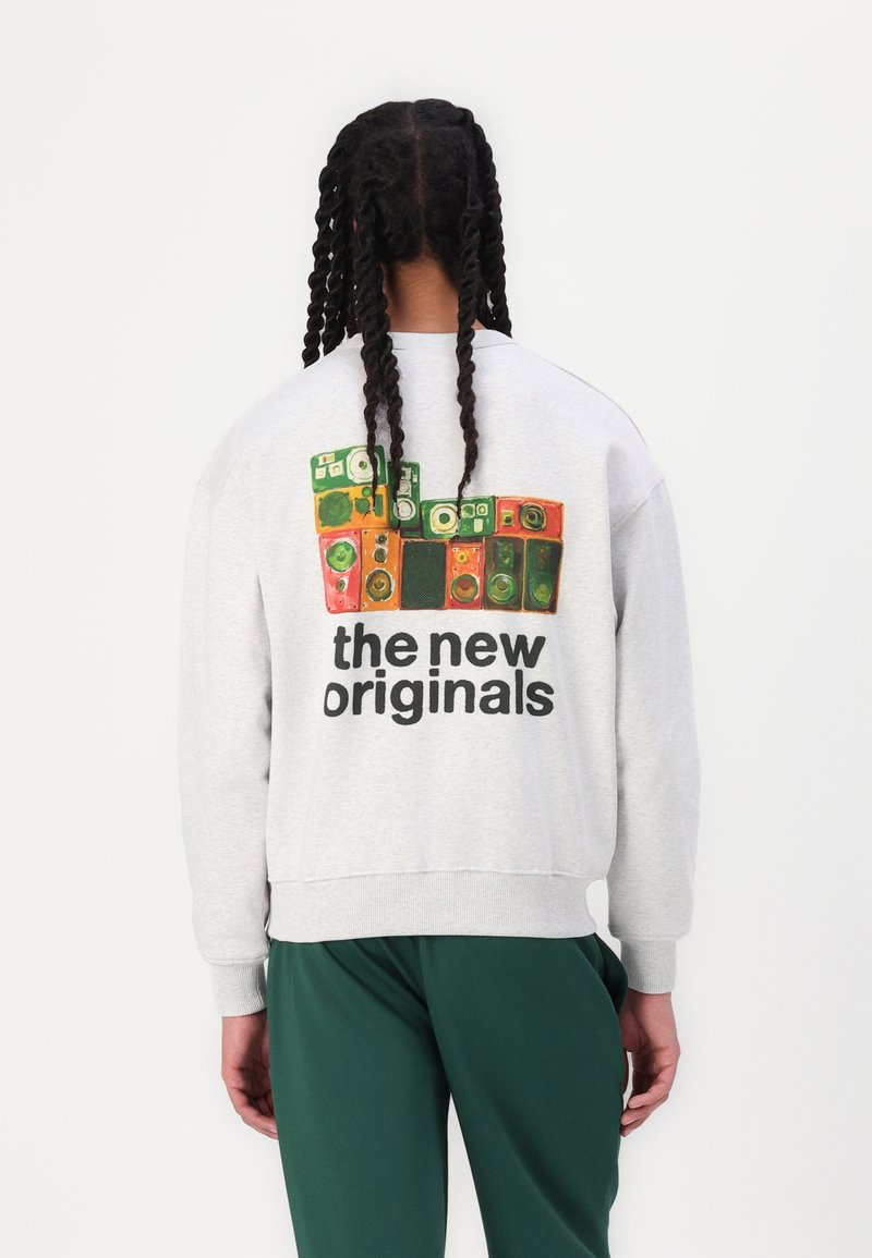 Grå hettegenser med et baktrykk av fargerike høyttalerdesign og teksten "de nye originalene." Passer avslappet med ribbestrikkede mansjetter og kant.