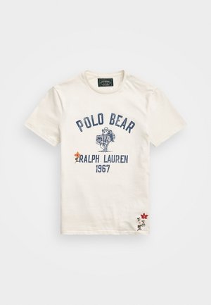 Camiseta blanca de manga corta con el texto "Polo Bear Ralph Lauren 1967", una ilustración de un oso y pequeñas flores bordadas en rojo y naranja.