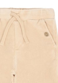 Beżowe spodnie z korduroyu z elastycznym pasem i sznurkiem. Posiadają boczne kieszenie oraz mały dekoracyjny guzik.