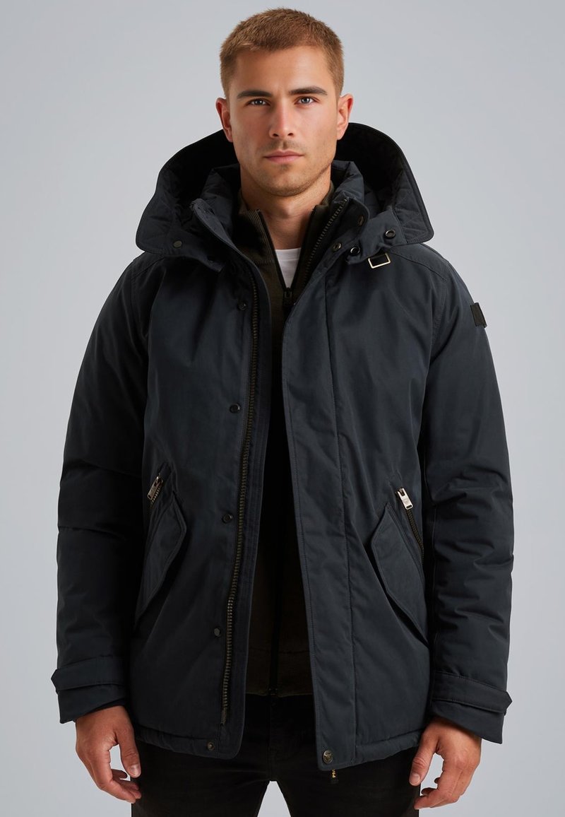 Črna izolirana jakna z veliko kapuco, zadrženimi žepi in gladko, rahlo sijočo površino. Dodatki vključujejo srebrno kovinsko opremo.