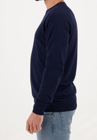 Marinblå tröja med rund hals och långa ärmar, ribbade manschetter och nederkant. Tillverkad av ett mjukt, slätt tyg och har en figurnära design.