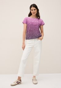 Kortärmad topp i gradient lila med en texturerad mönster, med texten "ENDLESS NATURE", i kombination med vita vida byxor och avslappnade skor.